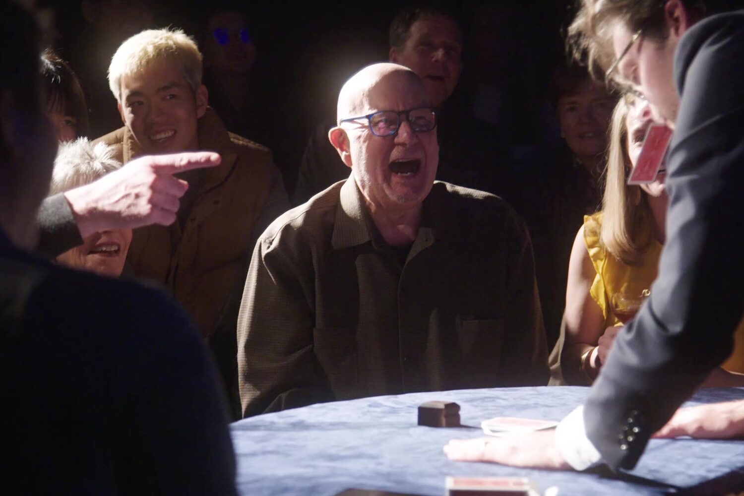 An audience member reacts with astonishment at Kevin Blake's card table